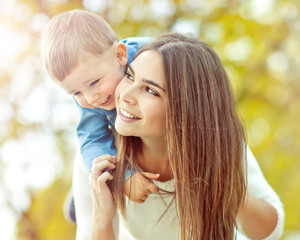 Happy mother are walking with her son in autumn park  