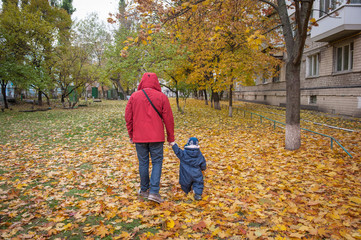 father's hand lead his child son in autumn park nature outdoor, trust family concept