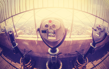 Vintage toned binoculars over Manhattan skyline at sunset, NYC.