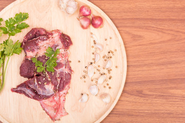 fresh raw beef meat slices and garlic, pepper on wooden