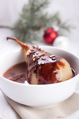Pear poached in white wine with chocolate sauce and nuts for Christmas.