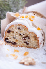 German dresdner stollen cake with raisins and candied oranges on a white background with false snow