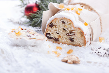 German dresdner stollen cake with raisins and candied oranges on a white background with false snow.