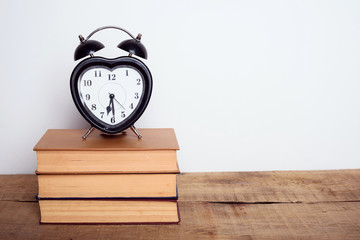 books and alarm clock on wooden background. Education equipment, education concept
