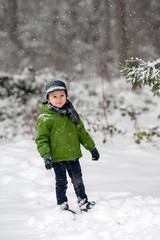 Fototapeta na wymiar Adorable little boy, blowing snowflakes outside in a snowy day