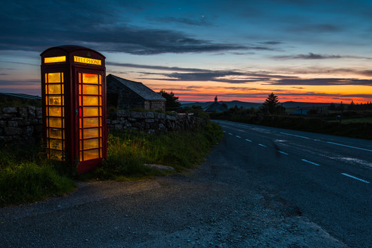 Red phone booth in English countryside at night