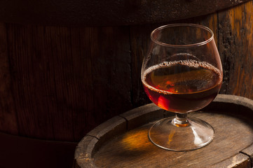 Glasses of brandy in cellar with old barrels
