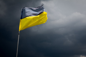 Torn Ukrainian flag on the background of a stormy sky