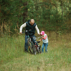 Fototapeta na wymiar father and daughter riding bike in the forest