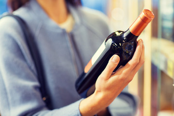 happy woman choosing and buying wine in market