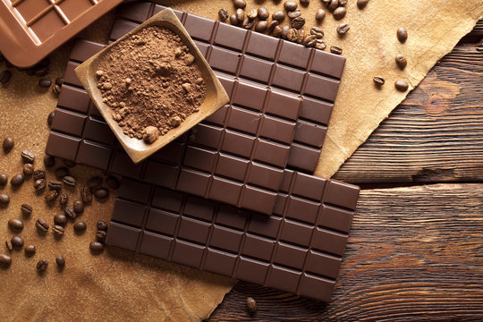 Chocolate, cocoa and coffee beans on wooden and paper background