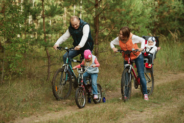 Fototapeta na wymiar happy family riding bike in wood