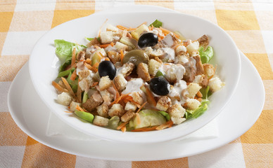Delicious salad of fresh vegetables, carrot, cucumber, cabbage, lettuce, served in a white bowl.
