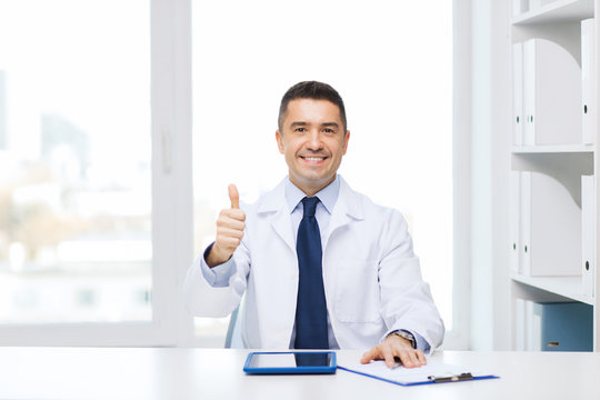 smiling doctor with tablet pc showing thumbs up