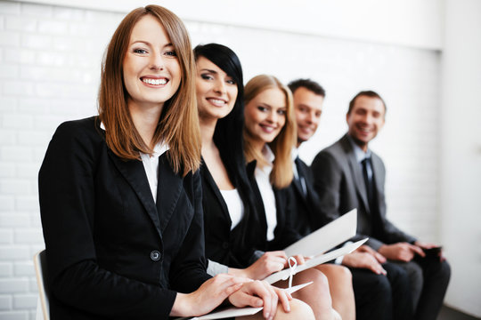 Cheerful business woman sitting wiht other professionals waiting for interview