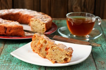 Homemade apple cake and black tea in glass cup on old wooden tab