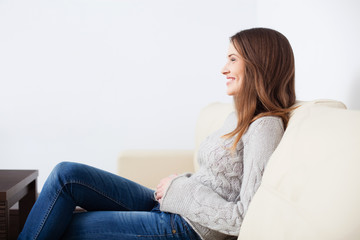 Obraz premium Young happy woman sitting on sofa