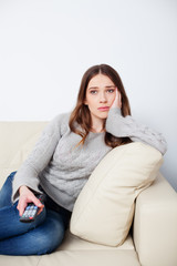 Obraz premium Sad woman watching television and changing channels