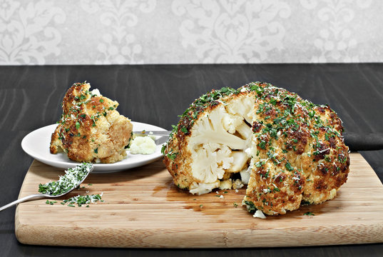 One Whole Roasted Cauliflower Head With A Slice Removed.