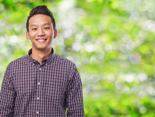 Handsome young asian man smiling wearing a plaid shirt