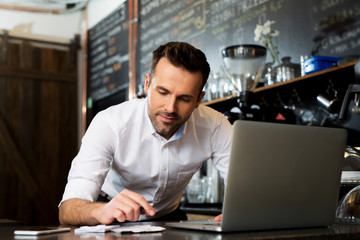 Cafe manager counting recipes with laptop