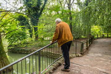 Obraz na płótnie Canvas Senior leaning against railing watching pond