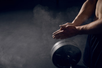 Closeup of athlete clapping hands before lifting barbells