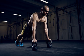 Fototapeta na wymiar Athlete making push ups on kettlebells for better strength