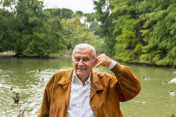 Fototapeta premium Senior makes the gesture of the phone with hand