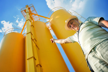 Farmer And Silos / A farmer in his mature wheat field, silos in the background © guruXOX