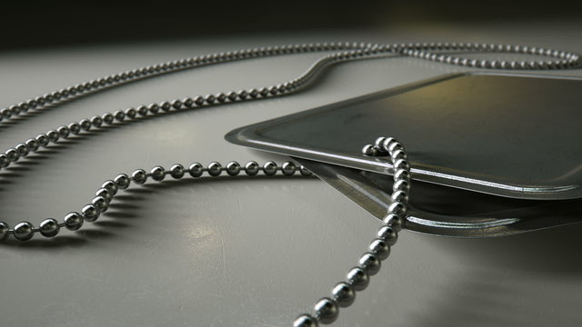 A macro pan across a regular set of blank military dog tag identity tags attached to a chain draped on an isolated dramatic background