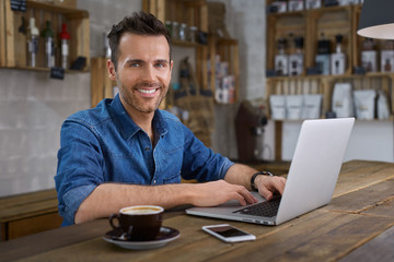 Handsome man sitting at cafe with laptop