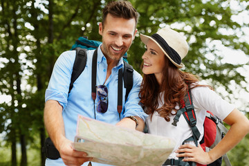 Happy couple hiking and reading map