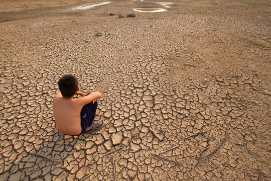 Children sitting on cracked earth, Metaphor for Global warming and Climate change.