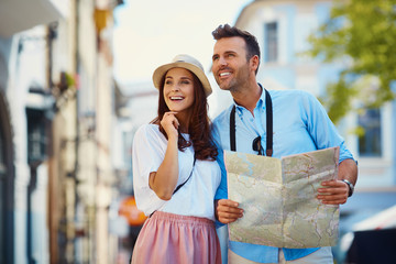 Happy couple with map visiting city