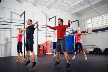 Obraz premium Group of people doing jumping jacks at gym