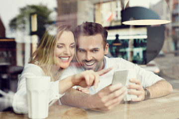 Couple using smartphone in coffee shop