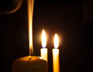 extinguished candle in front of two burning ones, macro
