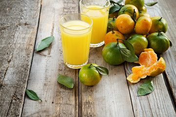 Organic tangerines and juice on a wooden background