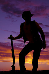 silhouette of cowboy with shotgun funny pose in sunset