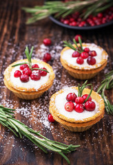 Tartlets of pastry with cream and fresh berries ripe cranberries, rosemary leaves