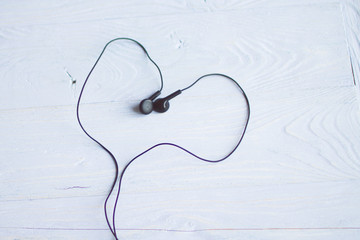Headphones on a wooden background in the form of heart
