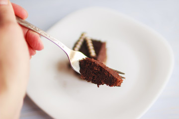 hand holding a fork with a piece of cake
