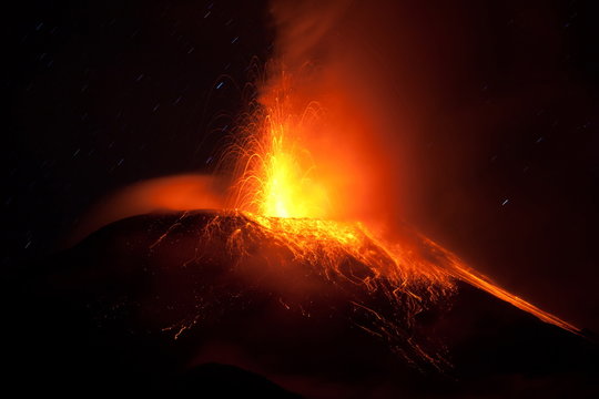 A fiery volcano erupting with red lava, casting a glowing red hue over the landscape as magma and dust explode into the air.