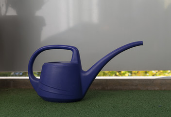 A watering can on a balcony with plastic grass © lasselund