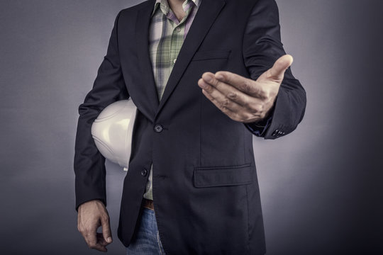 Closeup of an  architect man holding white hardhat under his arm