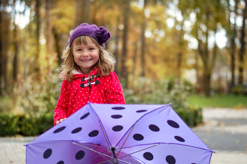 Little girl standing behind purple umbrella
