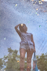 a reflection of a young girl in a puddle after rain.