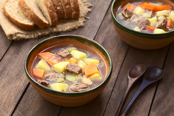 Traditional Hungarian soup called Gulyasleves made of beef, potato, carrot, onion, csipetke (homemade pasta) (Selective Focus, Focus in the middle of the soup in the first bowl)