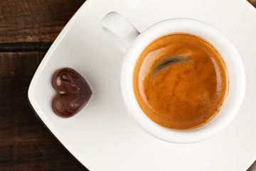 A delicious Colombian espresso topped with rich dark chocolate foam and cream, served on a wooden spoon in the shape of a heart.
